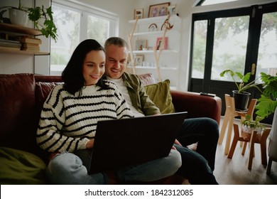 Portrait of young happy couple sitting together using laptop
