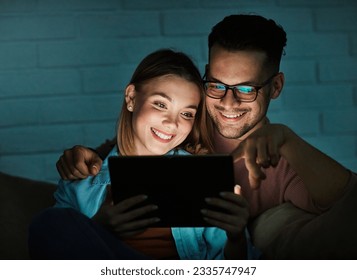 Portrait of young happy couple using tablet computer at night, using modern technology having fun with glowing screen in dark office or at home, watching tv together at home. Shot of a couple resting  - Powered by Shutterstock