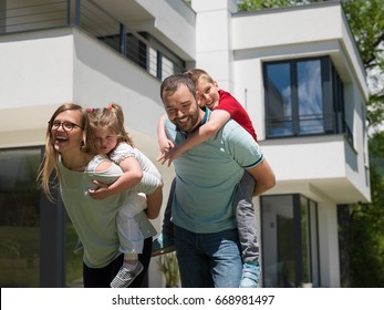 Portrait Of Young Happy Family With Children In The Yard In Front Of Their Luxury Home Of Villa