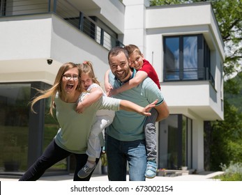 Portrait Of Young Happy Family With Children In The Yard In Front Of Their Luxury Home Of Villa