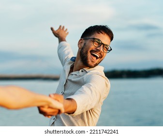 Portrait of a young happy man and couple having fun outdoors in nature during sunset. Girlfriend and boyfriend bonding, love concept during summer, holding hands and dancing and swinging
