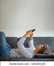 Portrait Young Happy Man Relaxing On Couch Looking At Phone 