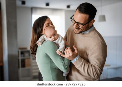 Portrait of young happy man and woman holding newborn cute babe dressed in white unisex clothing. - Powered by Shutterstock