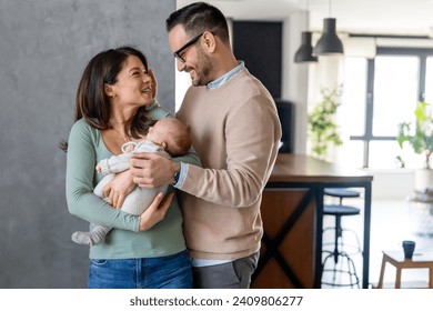 Portrait of young happy man and woman holding newborn cute babe dressed in white unisex clothing. - Powered by Shutterstock