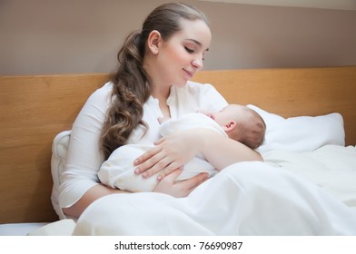 Portrait Of Young Happy Mother With Newborn Baby At Home