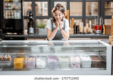 Portrait of a young and happy saleswoman at the counter in ice cream shop or cafe. Concept of a small business and retail