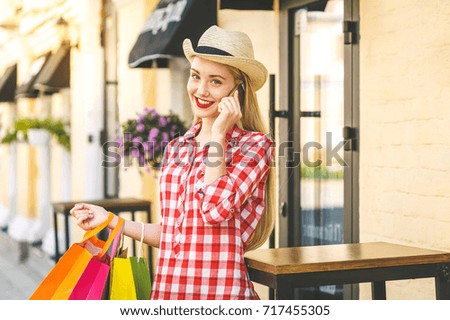 Portrait of young happy smiling woman with phone. Young woman holding shopping bags. Online shopping concept