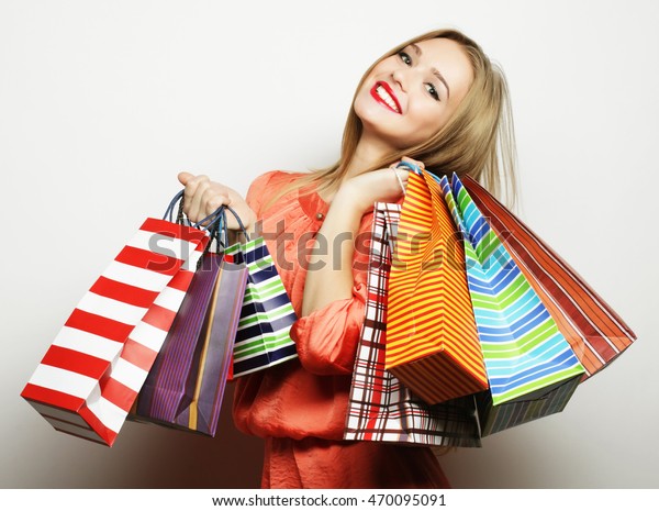 Portrait of young happy smiling woman with shopping bags, over white background