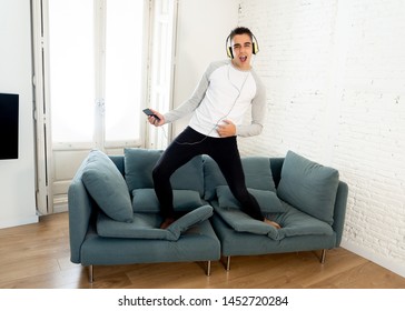 Portrait of young happy teenager male listening to music in headphones singing and dancing on couch sofa having fun at home. In positive emotions and happiness,Leisure Music and technology concept. - Shutterstock ID 1452720284