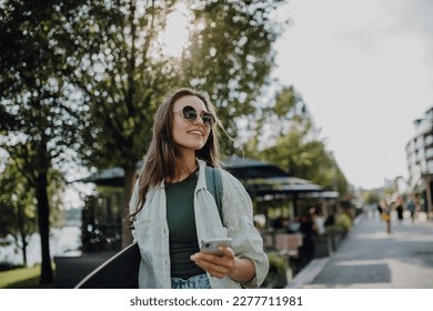 Portrait of young happy woman outdoor with skateboard. Youth culture and commuting concept.
