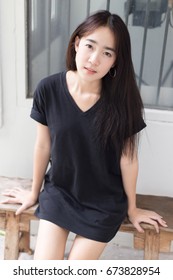 Portrait Of Young High School Asian Woman Wearing Black Hiphop T-shirt Sitting Down At Home With Happy Emotional