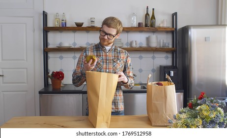 Portrait Of Young Hipster Guy Coming Home From Shopping Carrying Paper Shopping Bags With Groceries. Guy Bringing Food Home. Household And Food Concept