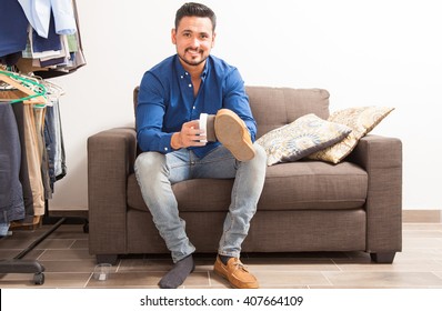 Portrait Of A Young Hispanic Man With A Beard Polishing His Shoes In A Dressing Room And Getting Ready For Work