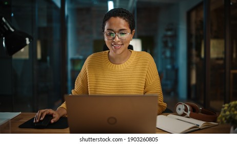 Portrait Of Young Hispanic Marketing Specialist Working On Laptop Computer In Busy Creative Office Environment. Beautiful Diverse Multiethnic Female Project Manager Is Browsing Internet.