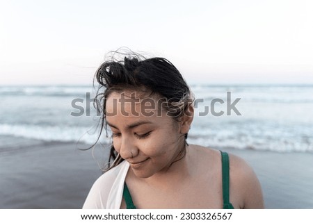 Portrait of a young Hispanic woman posing relaxed in front of the sea at the beach