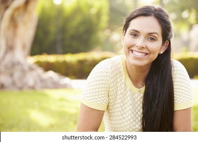 Portrait Of Young Hispanic Woman Sitting In Park