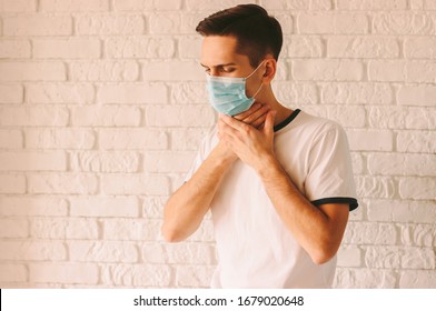 Retrato de un joven enfermo con máscara de protección médica en la cara que sufre de dolor de garganta. Paciente enfermo con dolor de garganta y tos. Síntomas típicos de la agina, el coronavirus COVID-19 o la gripe