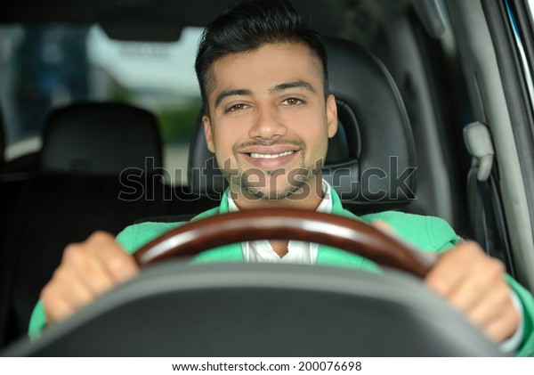 Portrait of\
young Indian business man, driving a\
car
