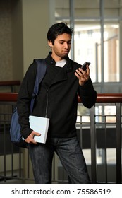 Portrait Of Young Indian Student Using Cell Phone Indoors