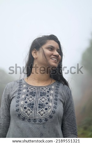 A portrait of a young Indian woman enjoying monsoon season on a foggy day at Amboli Ghats, Maharashtra, India.
