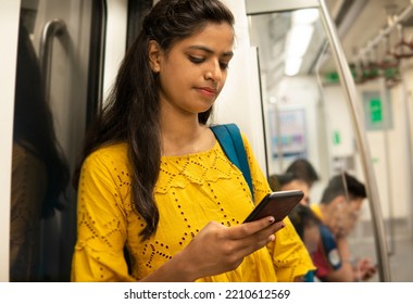 Portrait of young Indian woman passenger traveling in the metro and using a smartphone.  