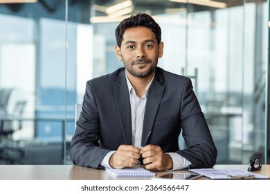 Portrait of a young investor banker at the workplace inside the bank office, a businessman in a business suit looking friendly at the camera, a man at work. - Powered by Shutterstock