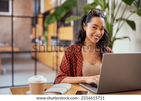 Portrait of young latin business woman working on laptop. Woman entrepreneur working on laptop in modern creative office with copy space. Multiethnic mexican student studying online on computer.