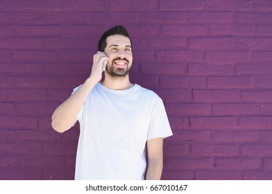 Portrait of young latin man talking on the phone against brick wall. Outdoors. - Powered by Shutterstock