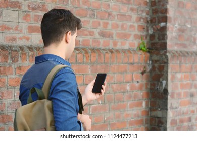 Porträt eines jungen Latiners, der auf sein Telefon tippt. Draußen.