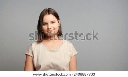 Portrait of young latin teenager female student in beige t-shirt, smiling isolated on gray background. Copy space.