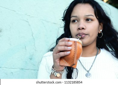 Portrait of Young latin woman drinking traditional Argentinian yerba mate tea. South american popular drink. Outdoors