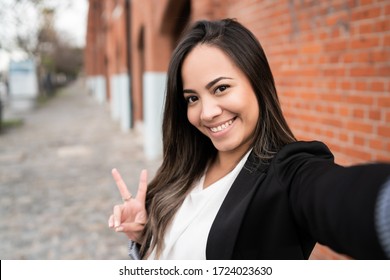 Portrait of young latin woman taking a selfie outdoors in the street. - Shutterstock ID 1724023630