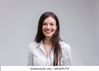 Portrait Of Young Long-haired Cheerful Woman Wearing White Shirt Against Plain Background