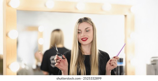 Portrait of young lovely professional master holding tools for work and posing. Qualified hairdresser hold scissors and comb. Beauty studio, barber concept - Powered by Shutterstock