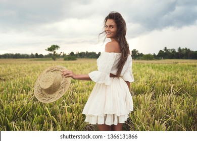 Portrait of young lovely woman holding straw hat in the rice field