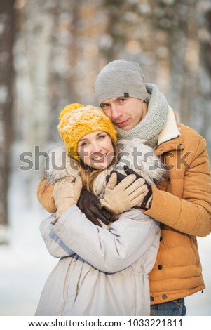 Portrait of young loving couple in a grey and orange color of clothes in a winter forest