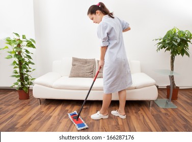 Portrait Of A Young Maid In Uniform Cleaning Floor With Mop