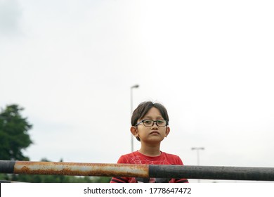 A Portrait Of Young Malay Boy Wearing Glasses Outdoor.