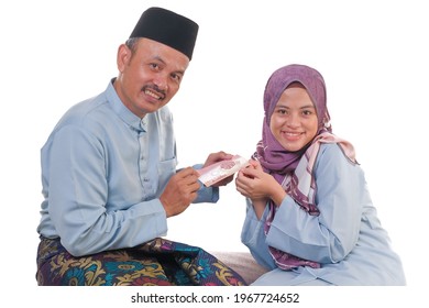 A Portrait Of Young Malay Girl With Surprise Happy Expression, Holding An Envelope Of Pocket Money Of Malaysian Currency. Translation On The Envelope : Happy Eid Mubarak. Raya Concept.