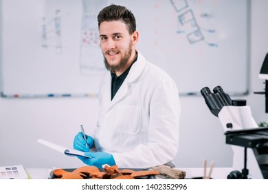 Portrait Of Young Male Archaeology Student With Microscope In Laboratory.