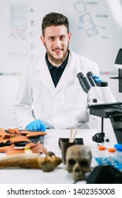 Portrait Of Young Male Archaeology Student With Microscope In Laboratory.