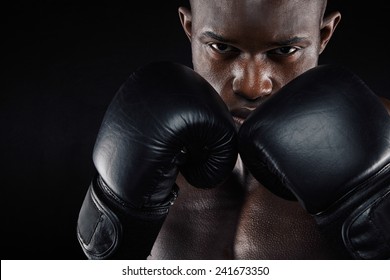 Portrait of a young male boxer in a fighting stance on black background. Young man doing boxing exercise. - Powered by Shutterstock