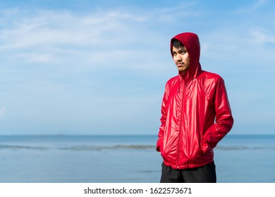 Portrait of a young male boxer in red hoodie jacket practicing boxing on beach against blue sky - Powered by Shutterstock