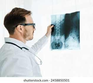 Portrait of a young male doctor looking at a x-ray of spine and back in his office in hospital - Powered by Shutterstock