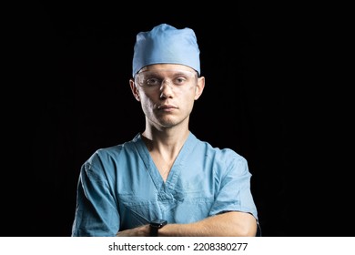 Portrait Of A Young Male Doctor In Uniform And Glasses On A Dark Background.