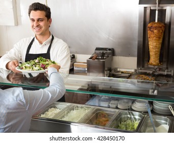 Portrait Of A Young Male Fast Food Worker At Counter Of Kebab Cafe