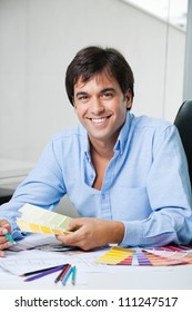 Portrait Of Young Male Interior Designer Smiling While Holding Color Swatches