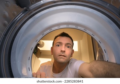 Portrait of young male mechanic repairing washing machine at home