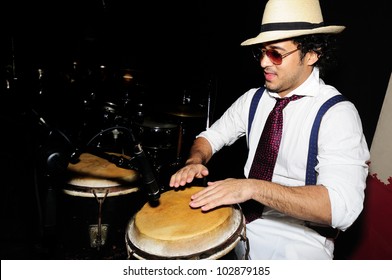 Portrait Of Young Male Percussionist Playing Cuban Drums Against Black Background