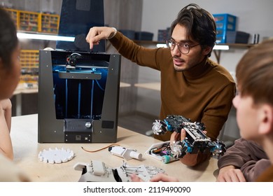 Portrait Of Young Male Teacher Showing 3D Printing Technology To Children In Robotics Class At School